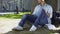 Multiracial male in headphones sitting under tree, listening to favorite music