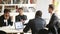 Multiracial male partners discussing business document at meeting in boardroom