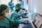 Multiracial medical scientist in hazmat suit working with microscope and laptop computer inside modern laboratory hospital - Focus