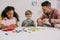 multiracial preschoolers and teacher with plasticine sculpturing figures at table