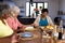 Multiracial senior female friends holding hands and saying grace at dining table in nursing home