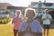 Multiracial seniors meditating while standing against retirement home in yard on sunny day