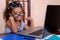 Multiracial small girl wearing glasses and using a laptop comput