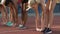 Multiracial students leaning forward stretching legs, doing exercises at stadium