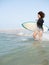 Multiracial surfer girl running to the waves on the beach shore