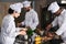 Multiracial team of cooks cooking by kitchen stove