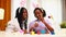 multiracial two women painting eggs with cute pink rabbit costume ears in apartment