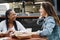 Multiracial women eating at food truck restaurant outdoor - Focus on african woman face