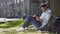 Multiracial young guy sitting under tree, reading interesting book, bookworm