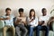 Multiracial young people using smartphones waiting in queue