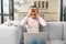 Multiracial young woman is tired, looking at computer screen and holding head