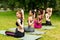 Multiracial young women locking hands behind their backs during yoga practice at park, copy space