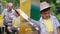 multiscreen, cute adorable male child helps his beloved grandfather paint an old beehive with paintbrush with yellow