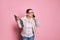 Multitasking overworked busy pregnant woman holding laptop and arguing while talking on mobile phone on pink backdrop