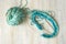 Multycolored turquoise thread clew ball, knitting needles and knitted fabric on white bleached wood