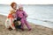 Mum with children sit on river bank