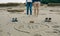 Mum, dad and baby written on the sand with the parents behind