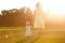 Mum daughter dresses barefooted legs hands grass sunset