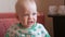 Mum feeds the beautiful baby with a spoon fruit porridge. The child looks at one point carefully. Close-up