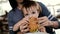 Mum feeds the child a tasty hamburger, cheeseburger