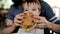 Mum feeds the child a tasty hamburger, cheeseburger