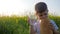 Mum gives child glass with clean water, hungry happy child eats food on meadow in backlight, youngster with loaf bread