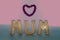 Mum in gold letters with pink love heart frame. Pastel colors.