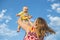 Mum lifts a child in his arms against the sky. Having fun outdoors, love and happiness concept