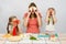 Mum with two little girls having fun at kitchen table playing with vegetables