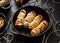 Mummy dogs made of sausages and puff pastry on a black background  close-up