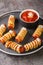 Mummy sausage in dough scary Halloween holiday food with funny eyes and sauce on a plate. vertical