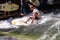 Munich, Germany - July 13, 2021: Surfer in the city river Eisbach. Munich is famous for surfing in urban enviroment