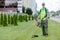 Municipal gardener landscaper worker with gas grass string trimmer