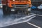 Municipal watering truck machines washes asphalt, process of street disinfection and cleaning from dust and dirt, cleaning flusher