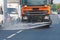 Municipal watering truck machines washes asphalt, process of street disinfection and cleaning from dust and dirt, cleaning flusher