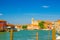 Murano islands water canal with Santa Maria degli Angeli church, boats and motor boats, row of traditional buildings