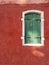 Murano, Italy - February 2019: First view of green wooden window, of a red house in Murano, Italy