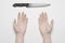 Murder and Halloween theme: A man\'s hand reaching for a knife, a human hand holding a knife isolated on a gray background in