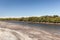 Murray River with a forest of Red Gum trees in the background and in the foreground a riverside shore bank