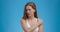 Muscle pain. Young woman suffering from pain in shoulder, blue studio background, slow motion