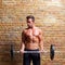 Muscle shaped body man with weights on brick wall