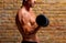 Muscle shaped body man with weights on brick wall