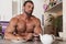 Muscle shirtless bachelor man have a breakfast in kitchen