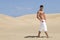Muscled man in the desert dunes with white trousse