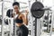 Muscular african female lifting heavy barbell pumping biceps in gym