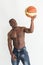 Muscular afro american athlete with basketball ball on white background