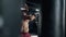 A muscular alone boxer is hits punching bag in the gym. Sportsman is boxing in dark hall. Self confident man is training