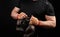 Muscular athlete in a black uniform holds very old brown boxing gloves in his hand, his hands are bandaged