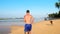 Muscular athlete in blue shorts runs along sandy coastline