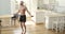 Muscular athletic man is jumping rope making cardio training at home in kitchen.